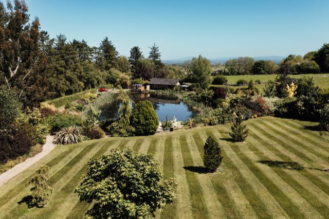 Luxury Lakeview Retreat: Aerial view over the striped lawns to the lake and lodge
