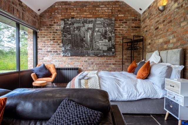 Luxury Lakeview Retreat: Super king bed against exposed brick, with seating in front