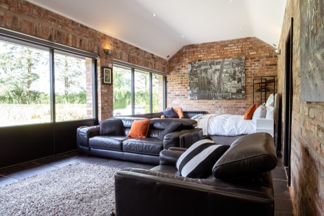 Luxury Lakeview Retreat: Living area and bed beside large garden windows