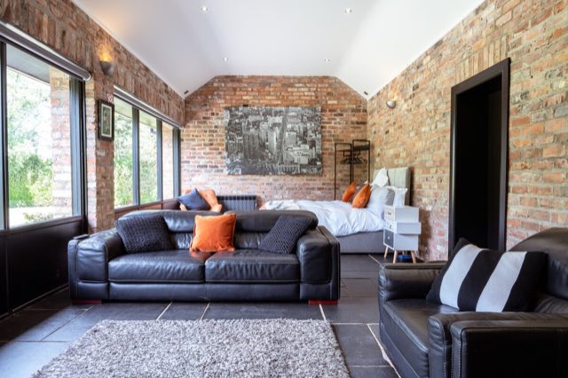 Luxury Lakeview Retreat: Leather sofas facing the bed in the open-plan room