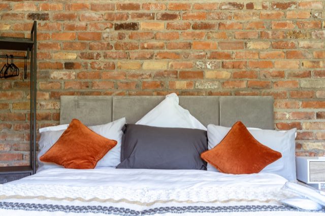 Luxury Lakeview Retreat: Super king bed with orange cushions against exposed brick