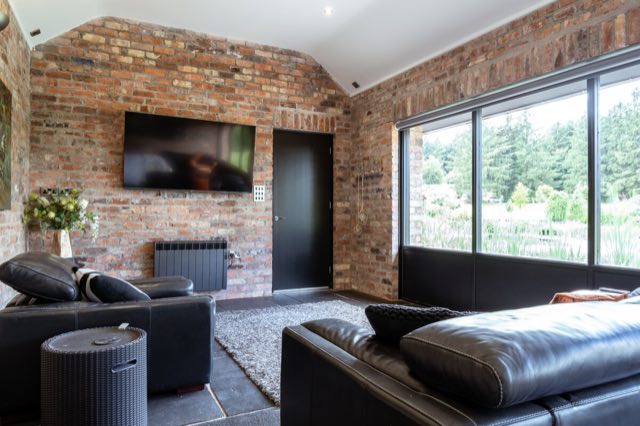 Luxury Lakeview Retreat: TV wall and large windows looking out to the garden